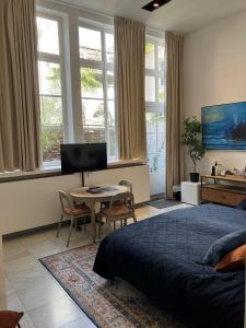 a bedroom with a bed and a table and windows at Galerie Hotel Dis in Maastricht