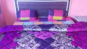 a bed with colorful sheets and pillows in a room at SPOT ON Sharma's Kitchen & Home Stay in Bajaura