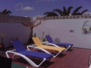 3 sillas sentadas en un patio junto a una pared en Villa Acoran, en Costa Teguise