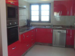 a kitchen with red cabinets and a sink and a window at Villa Acoran in Costa Teguise