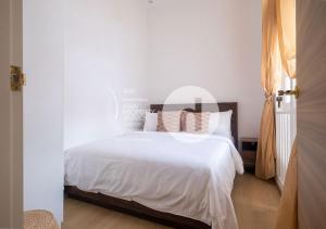 um quarto com uma cama com lençóis brancos e almofadas em hovoh homes Bugis Rochor em Singapura