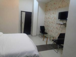 een slaapkamer met een bed en 2 stoelen en een televisie bij OYO Hotel Rajdeep in Agra