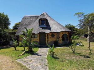 a small yellow house with a thatched roof at Yellowwood Forest Eco Retreat in Morganʼs Bay