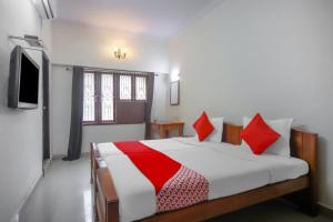 a bedroom with a bed with red pillows and a tv at OYO Home Tree Service Apartment Near Saravana Stores T Nagar in Chennai