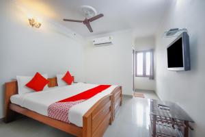 - une chambre avec un lit doté d'oreillers rouges et une télévision dans l'établissement OYO Home Tree Service Apartment Near Saravana Stores T Nagar, à Chennai