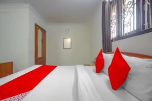 a bedroom with red pillows on a white bed at OYO Home Tree Service Apartment Near Saravana Stores T Nagar in Chennai