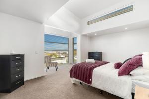 a white bedroom with a bed and a window at Lakeview Luxury - Taupo Holiday Apartment in Taupo
