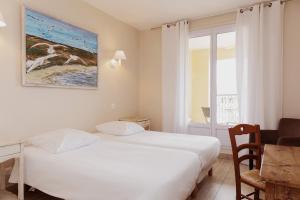Schlafzimmer mit einem Bett, einem Tisch und einem Fenster in der Unterkunft Coq Hotel in Cogolin