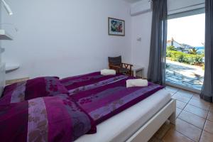 モコロスにあるBungalow Musuriのベッドルーム1室(紫のシーツが敷かれたベッド1台、窓付)