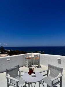 een tafel en stoelen op een balkon met uitzicht op de oceaan bij Nostos Studios in Parikia