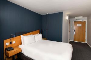 a bedroom with a large white bed and a blue wall at Holiday Inn Express Newcastle City Centre by IHG in Newcastle upon Tyne