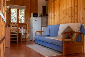 a living room with a blue couch and a kitchen at Las Casitas del Pinar in Bayubas de Abajo