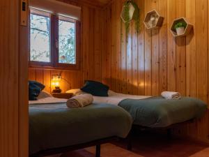 two beds in a room with wooden walls at Las Casitas del Pinar in Bayubas de Abajo