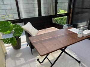 uma mesa e cadeira de madeira num quarto com uma janela em おもてなしハウスさいたま em Saitama