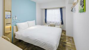 a bedroom with a white bed and a table at Toyoko Inn Osaka Bentencho in Osaka