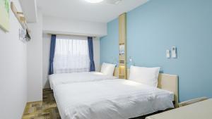 Duas camas num quarto com paredes azuis em Toyoko Inn Osaka Bentencho em Osaka