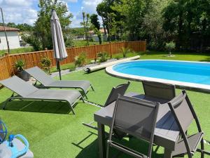 a backyard with a pool and chairs and an umbrella at Cocooning chez Sabine in Lavilledieu