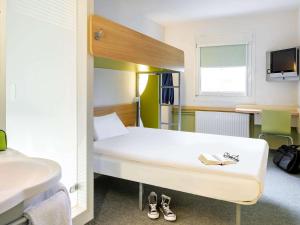 a room with a bed and a pair of shoes at ibis budget Aachen Nord in Aachen