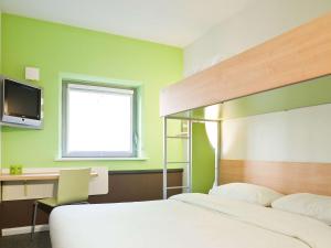 Dormitorio con cama, escritorio y TV en ibis budget Aachen Nord, en Aachen