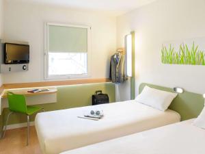 a room with two beds and a desk and a tv at Ibis budget Hamburg City Ost in Hamburg
