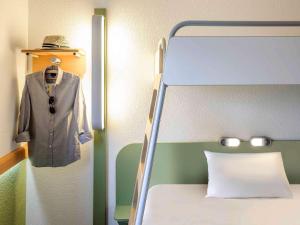 a bedroom with a bed and a suit on a rack at Ibis budget Hamburg City Ost in Hamburg
