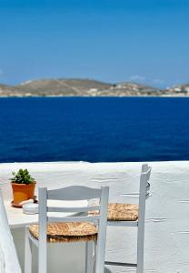 a table and two chairs sitting next to the ocean at Nostos Studios in Parikia