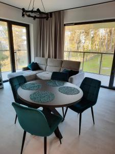 un salon avec une table, des chaises et un canapé dans l'établissement Apartament Słoneczny AKTENA Shellter Rogowo, à Rogowo