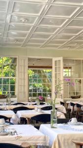une salle à manger avec des tables blanches, des chaises et des fenêtres dans l'établissement JANTZENs HOTEL, à Gudhjem