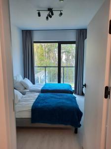 two beds in a bedroom with a large window at Apartament Słoneczny Shellter Rogowo in Rogowo