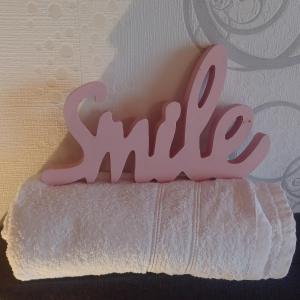 um sinal rosa que diz sorrir numa toalha branca em Zimmer und Apartment Rosi em Krakow am See