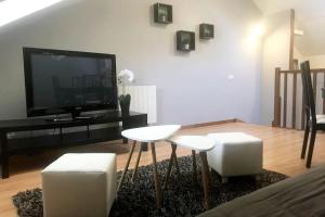 uma sala de estar com dois bancos brancos e uma televisão em Maison de ville, centre de Provins em Provins