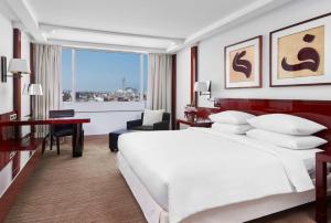 Habitación de hotel con cama blanca grande y escritorio. en Hyatt Regency Casablanca, en Casablanca