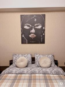 a bed with two pillows and a picture of a woman at RentHouse Apartments Relax Studio in Chişinău