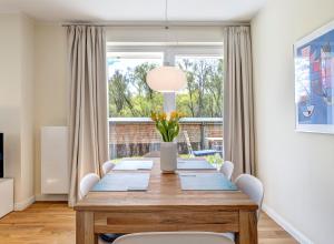 mesa de comedor con sillas blancas y ventana grande en Villa Madeleine App. 2 en Heringsdorf