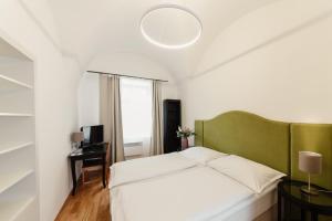 a bedroom with a white bed and a green headboard at Penzion Austis in Znojmo