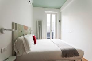 a bedroom with a large white bed with a red pillow at Brera Apartments in Nerino in Milan
