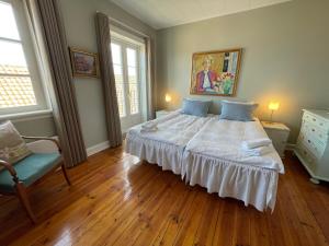 una camera con un grande letto bianco e una sedia di JANTZENs HOTEL a Gudhjem