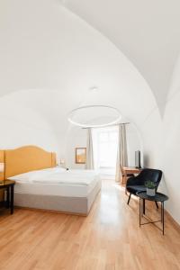 a white bedroom with a bed and a table at Penzion Austis in Znojmo