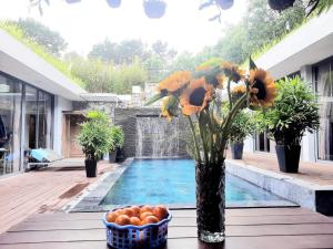 un jarrón con flores y naranjas en una mesa junto a una piscina en Flamingo Villa Đỗ Quyên en Vĩnh Phúc