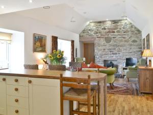 a kitchen and living room with a stone wall at Paterson Cottage in Tore