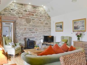 a living room with a couch and a stone wall at Paterson Cottage in Tore