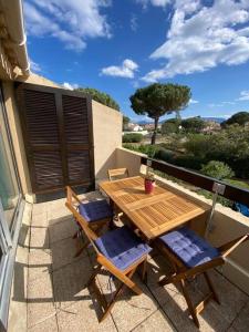 een houten tafel en stoelen op een balkon bij Grand studio entre le golf et la plage à 800m in Saint Cyprien Plage