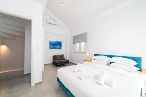 ein weißes Schlafzimmer mit einem großen Bett und einem Stuhl in der Unterkunft Dionysos Residential Complex in Ofrynio