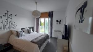 ein weißes Schlafzimmer mit einem Bett und einem TV in der Unterkunft Apartamento La Ilusión - Cariño in Cariño