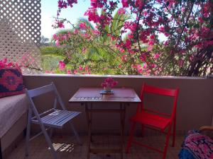 d'une table et de deux chaises sur un balcon orné de fleurs roses dans l'établissement BO-Piscine chauffée, Bénagil-Carvoeiro, à Carvoeiro
