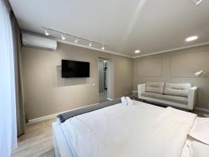 1 dormitorio con 1 cama blanca grande y 1 sofá en Luxury apartments en Pavlodar