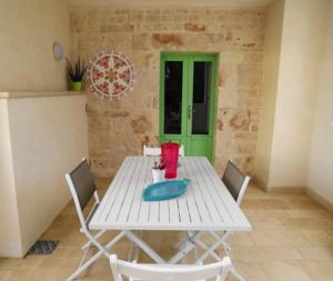 una mesa blanca y sillas en una habitación con puerta verde en trullo fino, en Cisternino