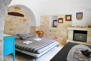 1 dormitorio con cama y pared de ladrillo en trullo fino, en Cisternino