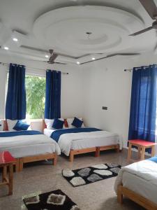 1 dormitorio con 2 camas y cortinas azules en The Spotted Dove Homestay, en Maneri