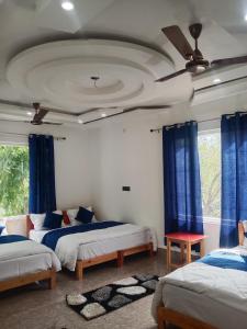 1 dormitorio con 2 camas y cortinas azules en The Spotted Dove Homestay, en Maneri